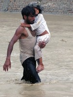 An Afghan man carries a young child to safety during encroaching flood waters in Nari Shahi village, Beshood District of eastern Afghanistan’s Nangarhar province July 28th. (U.S. Army courtesy photo) 