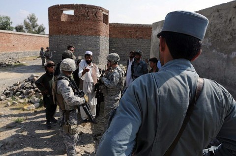 An Afghan National Policeman watches as Soldiers from the 330th Military Police Company meet with a village elder and discuss security concerns Oct. 7th. The Soldiers are working closely with approximately 300 ANP to help train and advise them on all aspects of law enforcement operations. (Photo by U.S. Army Staff Sgt. Brent C. Powell, 3rd Brigade, 101st Airborne Division)