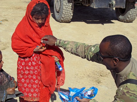 Master Sgt. Terrence Reyes, the operations NCOIC for Task Force Wings (4th Battalion, 101st Aviation Regiment) hands candy to an Afghan girl during a humanitarian visit here October 1st. TF Wings and TF 77 conducted a humanitarian assistance visit and key leader engagement at the Bolla Baba High School here.  (U.S. Army Photo by Staff Sgt. Joshua Dewitt, Task Force Wings Fire Support Officer /released)