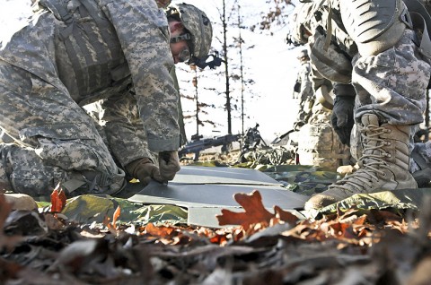 Pfc. Brian Nyers, a sapper with Company A, 1st Special Troops Battalion, 1st Brigade Combat Team, 101st Airborne Division, cuts holes into a cardboard silhouette as he and his group prepared to head down to the demolition range here Dec. 9th. (Photo by Sgt. Richard Daniels Jr.)