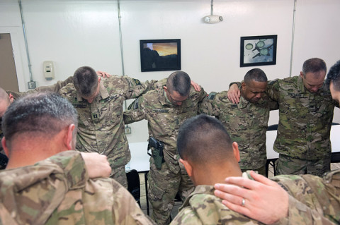 Soldiers conference huddle shoulder-to-shoulder in prayer at a breakfast concluding the 101st Combat Aviation Brigade, religious support team conference at Bagram Air Field, Afghanistan, Jan. 4th, 2013. (U.S. Army photo by Sgt. Duncan Brennan, 101st CAB public affairs)