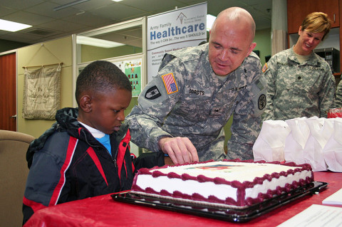 Blanchfield Army Community Hospital commander Col. Paul R. Cordts solicits the help from 5-year-old Justin Okoro to cut the cake February 1st during the kick-off to Patient Recognition Month at the hospital.