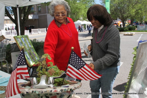 Two women admire a planter built into a sink at a booth in the Green Zone