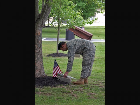 A Soldier from the 5th Special Forces Group (Airborne) places a rose on the marker of an oak tree on Gabriel Field during the Gold Star ceremony May 17, 2014, at Fort Campbell, Ky. Soldiers, Families, and friends, both past and present, gathered together to remember, reflect, and celebrate the lives of those that paid the ultimate sacrifice. (Sgt. Seth Plagenza)