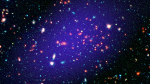 The galaxy cluster called MOO J1142+1527 can be seen here as it existed when light left it 8.5 billion years ago. The red galaxies at the center of the image make up the heart of the galaxy cluster. (NASA/JPL-Caltech/Gemini/CARMA)