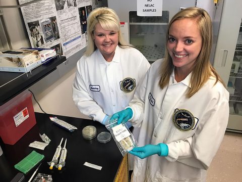 Sarah Wallace (L), NASA microbiologist and Genes in Space-3 principal investigator, and Sarah Stahl (R), microbiologist, are seen in their Johnson Space Center lab with the in-flight sample from the Genes in Space-3 investigation. (Rachel Barry)