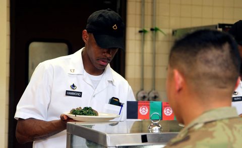 Private First Class Jeyson Hammond, a culinary specialist with Headquarters Support Company, Headquarters and Headquarters Battalion, 101st Airborne Division (Air Assault), prepares a plate for Maj. John Busuego, a Chemical, Biological, Radiological, and Nuclear officer with HSC, HHBN on Feb. 23, 2018 at the Oasis Dining Facility, Fort Campbell. Busuego brought his family to the Oasis Dining Facility to participate in the Afghan-inspired meal. (Capt. Jennifer Cruz, 40th Public Affairs Detachment)